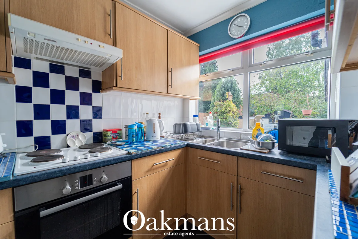 Modern kitchen with oak cabinetry, dark blue granite worktops, navy and white chequerboard tiles, gas hob, sink, microwa