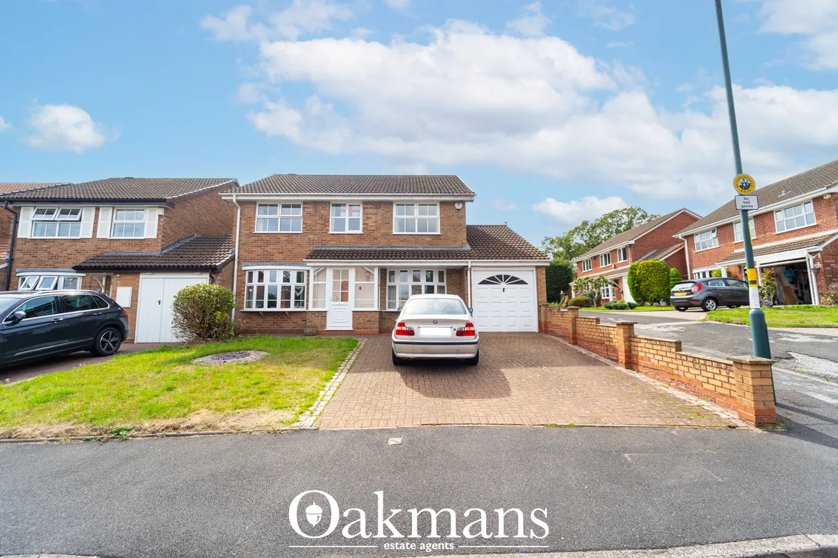 Brick detached house with driveway, white car, garage, manicured front lawn and neighbouring properties