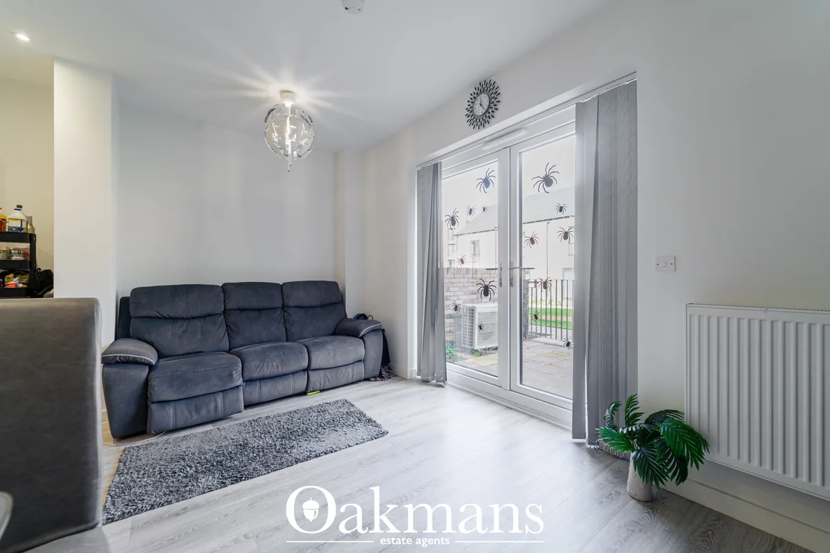 Bright living room with navy three-seat sofa, grey rug, patio doors to garden with palm tree decals, white radiator and 