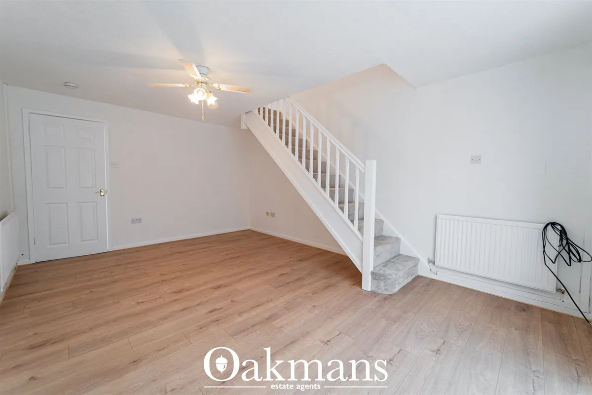 Bright hallway with wooden flooring, white staircase to upper level, radiator, ceiling fan and white painted walls
