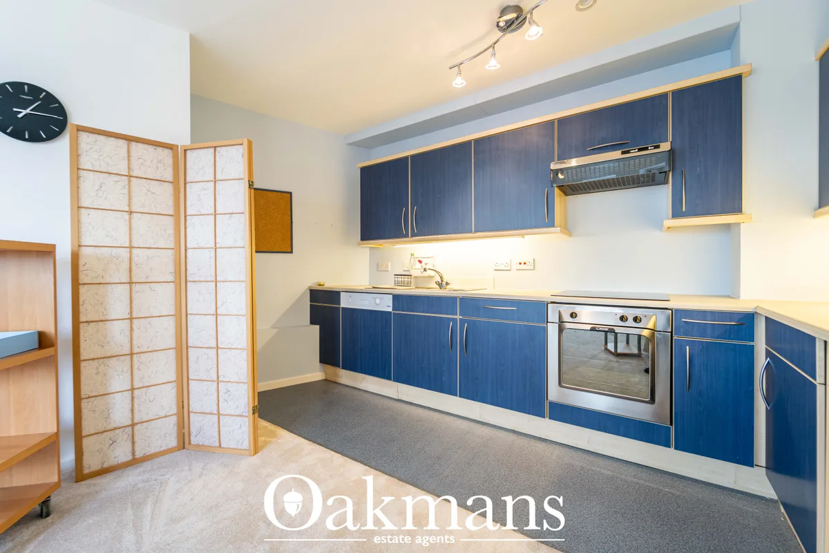 Modern fitted kitchen with navy blue cabinetry, wooden trim, stainless steel oven, granite worktops and track lighting