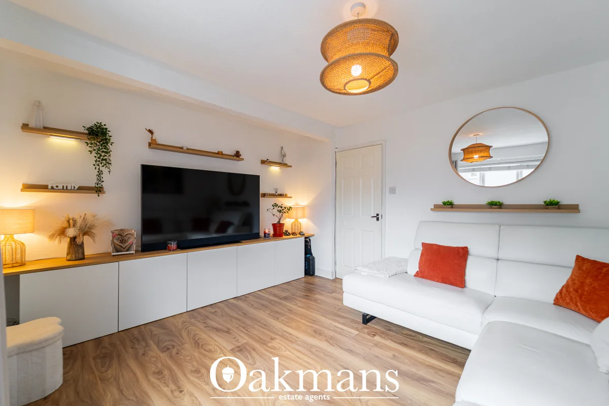Modern living room with white sofa, orange cushions, TV wall unit with wooden shelves, woven pendant light and wooden fl