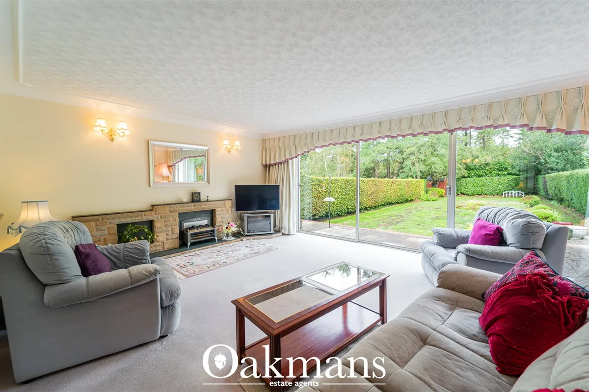 Spacious living room with grey upholstered sofas, fireplace with brick surround, large TV, coffee table, and extensive g