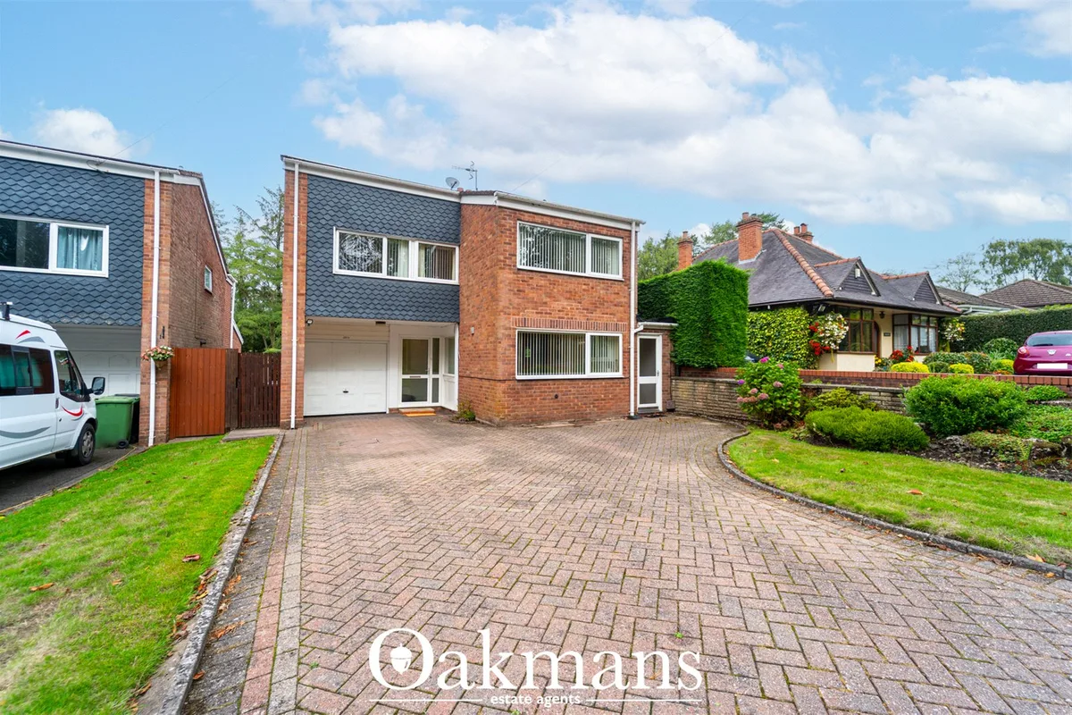 Red brick detached house with driveway, garage, manicured lawns and neighbouring properties visible