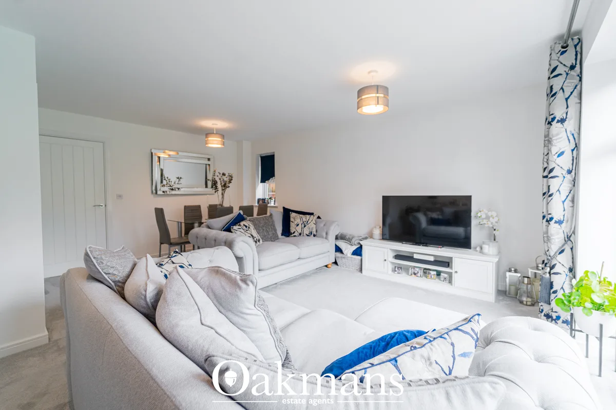 Open-plan living room with two cream sofas, flat-screen TV on white unit, blue and white soft furnishings, contemporary 