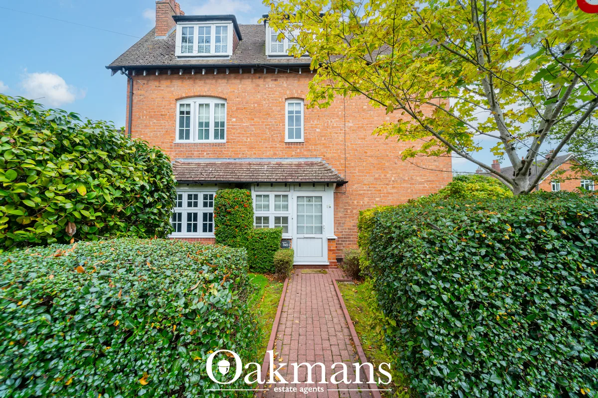 Red brick Victorian semi-detached house with white sash windows, dormer windows, manicured hedges and brick pathway lead