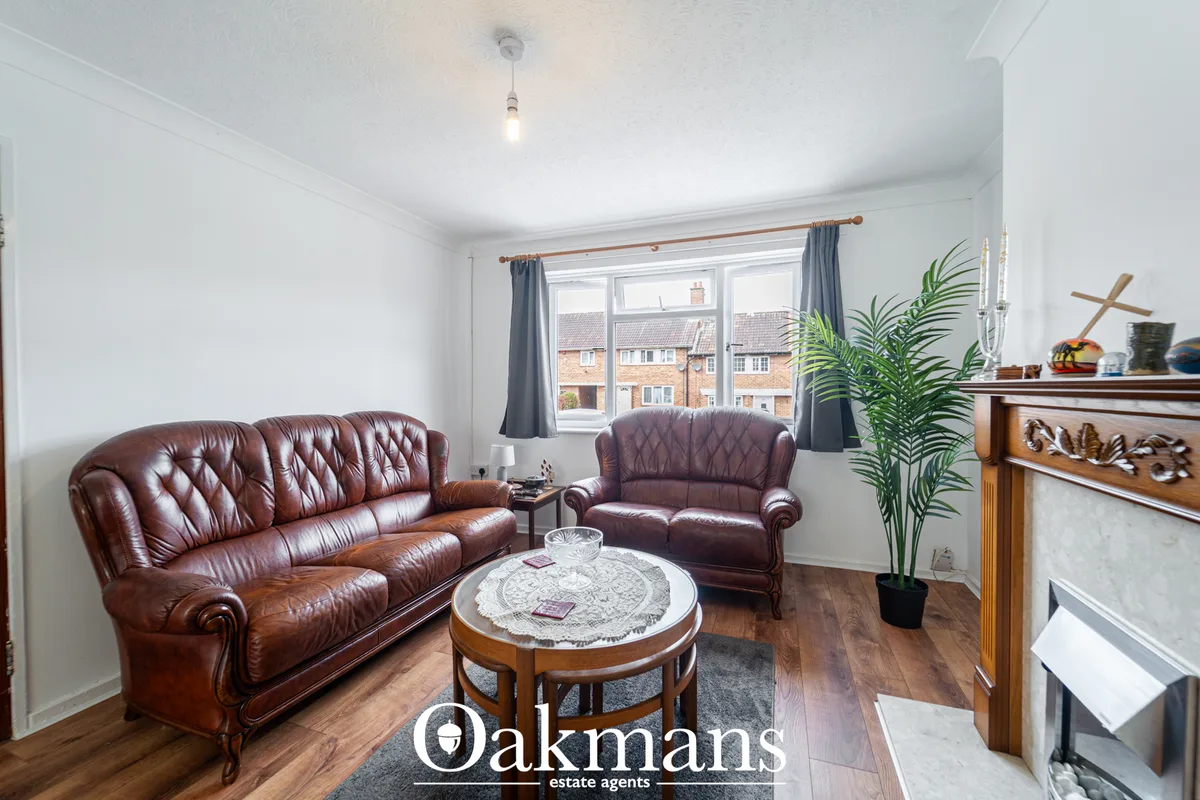 Bright living room with burgundy leather sofas, round wooden coffee table with lace doily, wooden fireplace mantel, pott