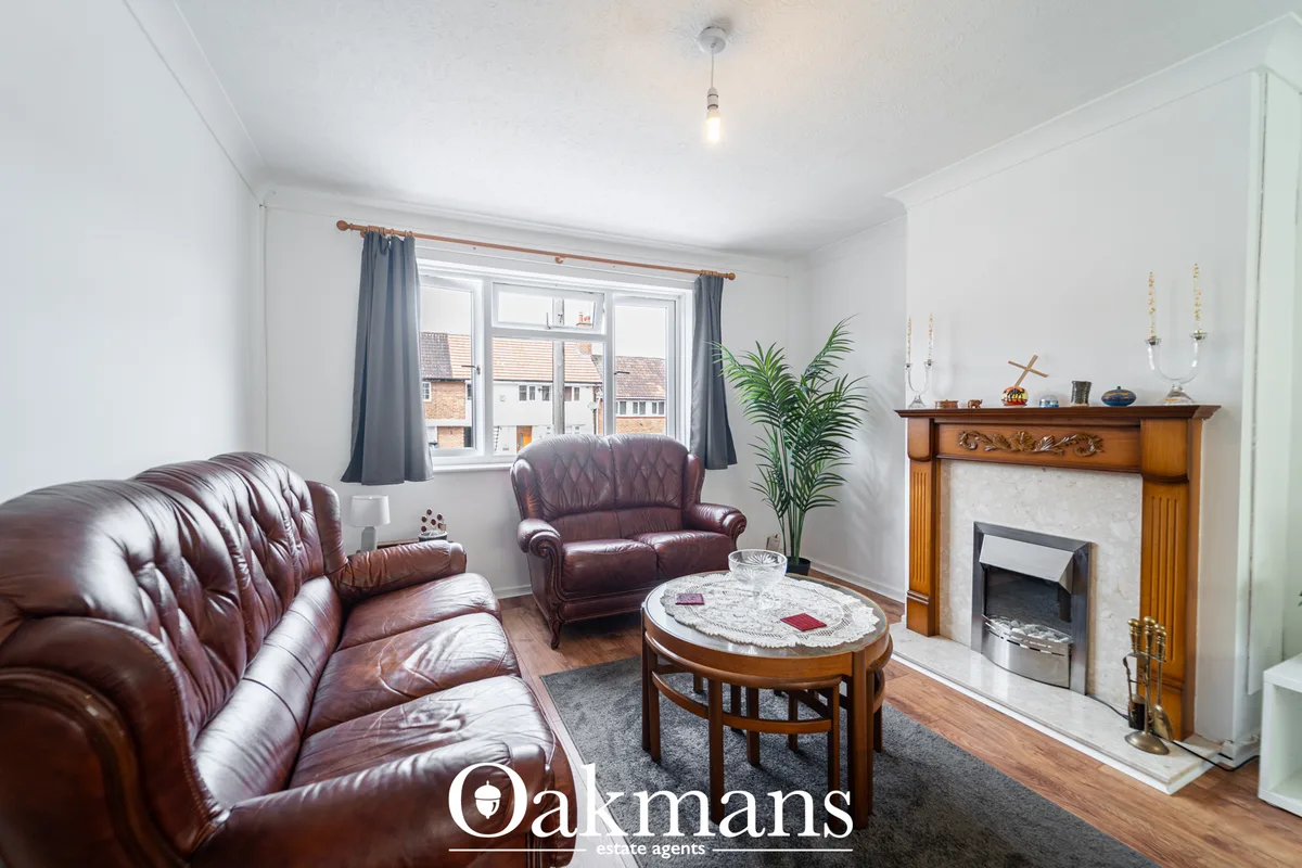 Bright living room with burgundy leather sofas, fireplace with wooden surround, oval marble coffee table, potted plant, 