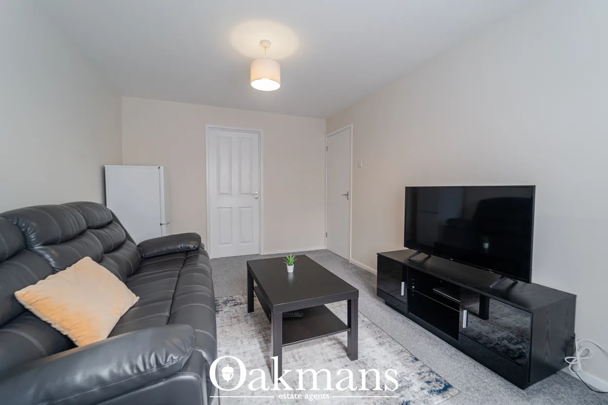 Spacious living room with black leather sofa, black coffee table, flat-screen TV on black stand, grey rug, and soft ceil