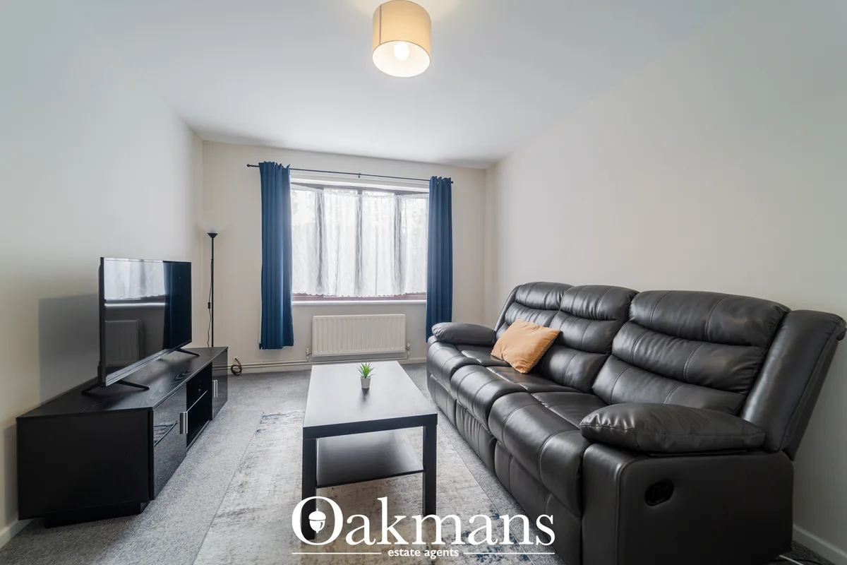 Modern living room with black leather reclining sofa, white coffee table, flat-screen TV on black unit, blue curtains an