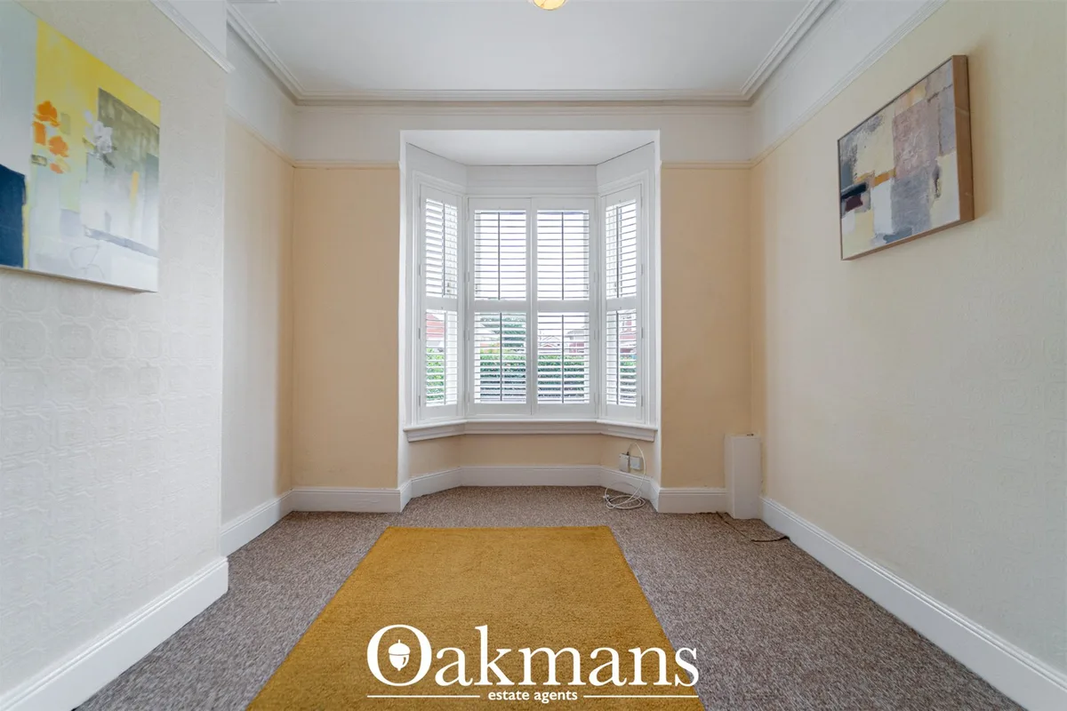 Bright hallway with cream and white walls, bay window with white shutters, mustard carpet runner, framed artwork, and pe