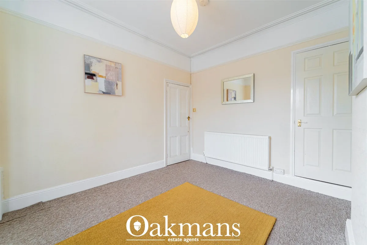 Spacious hallway with cream and white décor, beige carpet, pendant light fixture, radiator, and multiple white panel doo