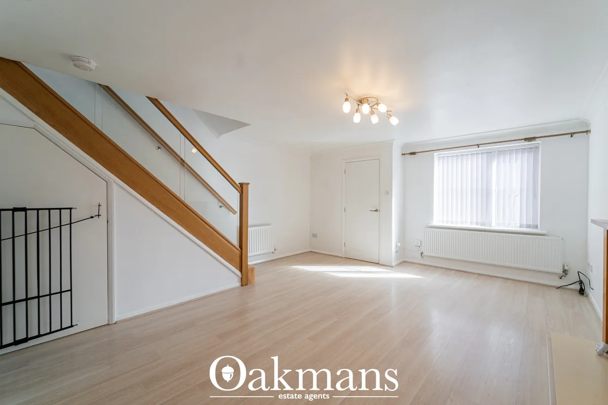 Bright open-plan living space with wooden staircase, laminate flooring, large window with vertical blinds, and modern ce