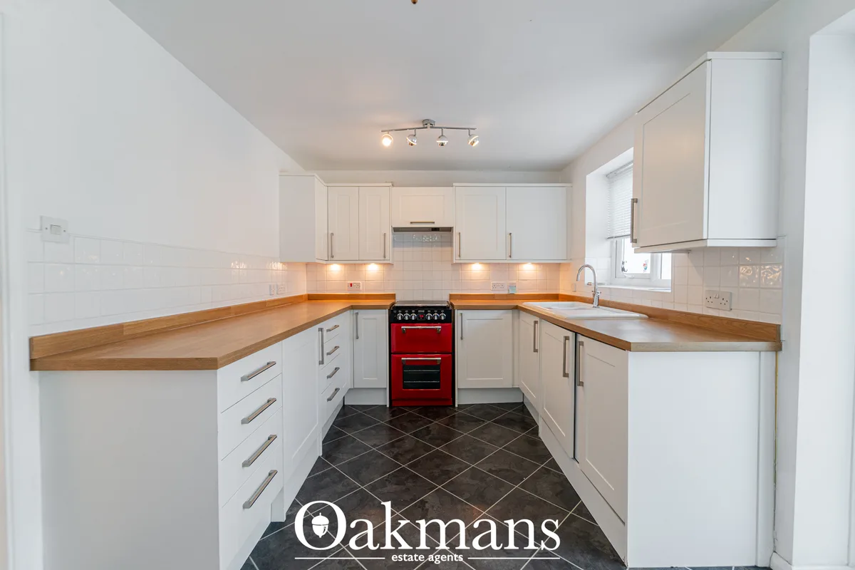 Modern fitted kitchen with white cabinetry, wooden worktops, red range cooker, white tile splashback and dark tiled floo
