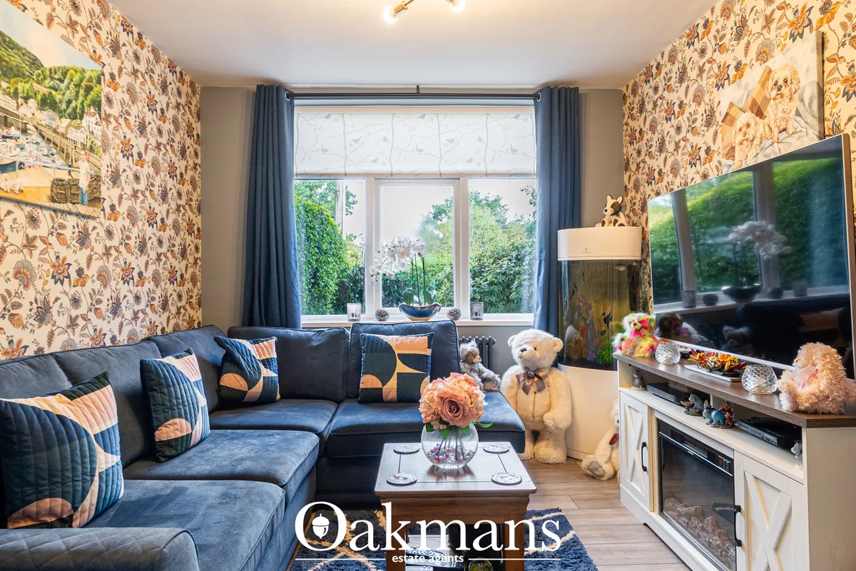 Stylish living room with navy blue corner sofa, patterned wallpaper, large window overlooking garden, flat-screen TV, an