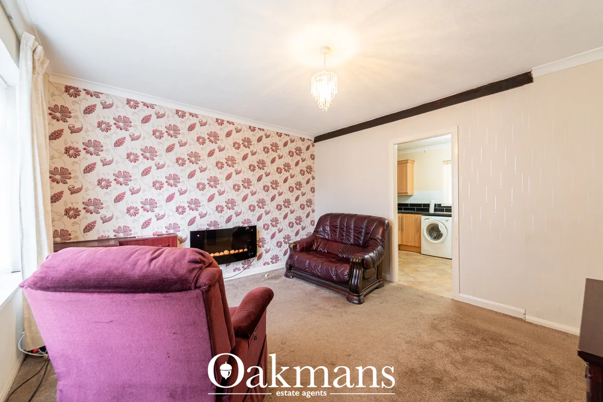 Spacious living room with red floral wallpaper, burgundy leather armchair, pink fabric chair, fireplace with decorative 