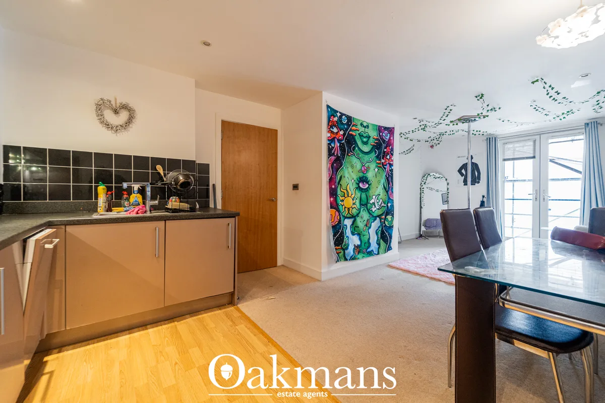 Open-plan living and dining space with beige carpet, glass dining table, dark chairs, colourful artwork, patio doors, an