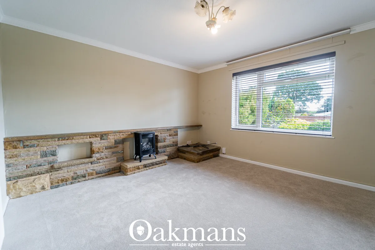 Spacious living room with stone fireplace feature, wood-burning stove, large window with views, cream walls and neutral 