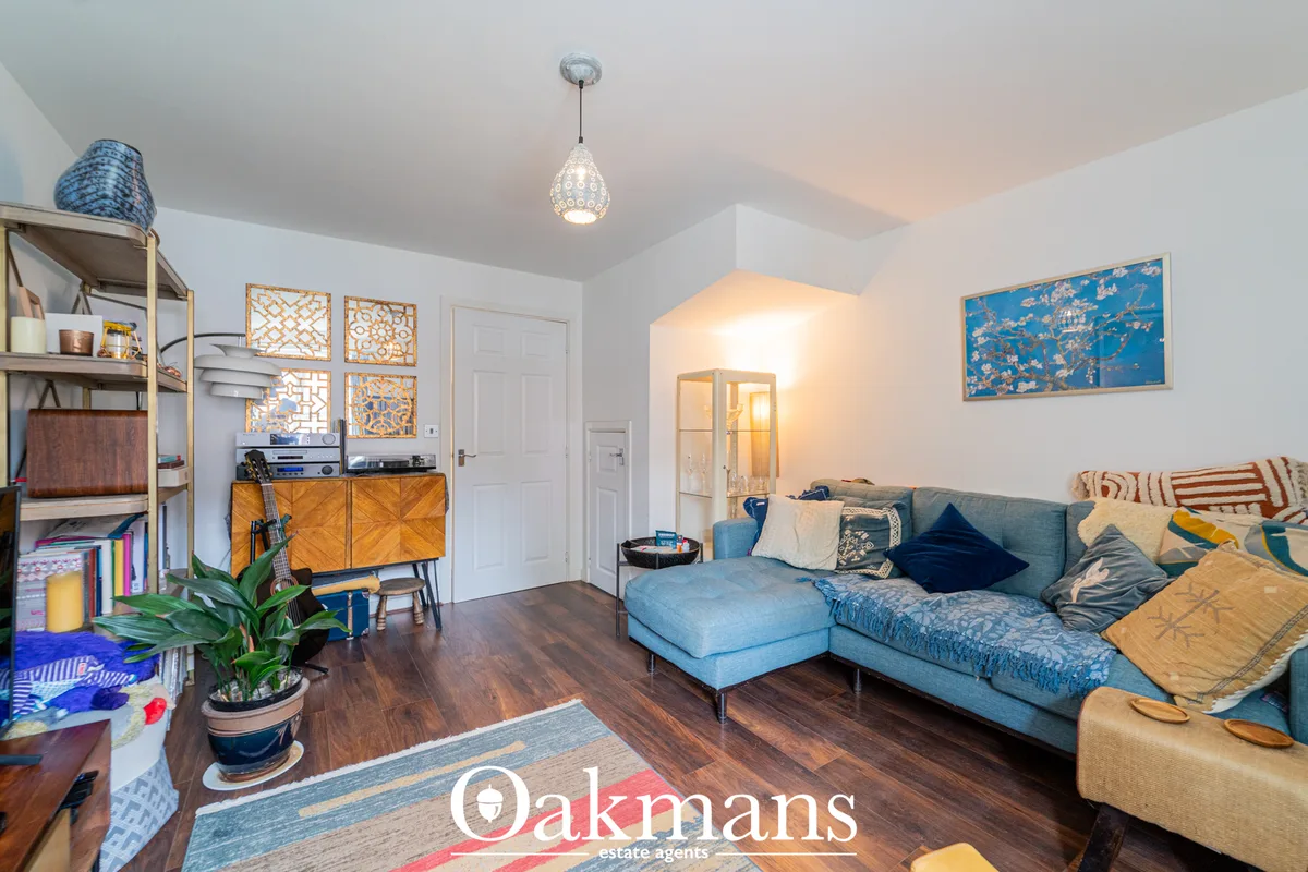 Bright living room with blue-grey corner sofa, wooden storage units, decorative wall art, pendant lighting and dark wood
