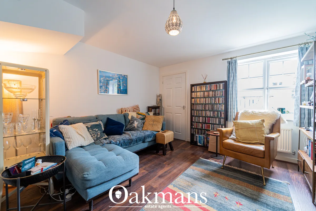Bright living room with blue sofa and chaise, tan leather armchair, bookshelf, pendant lighting, large windows with blue