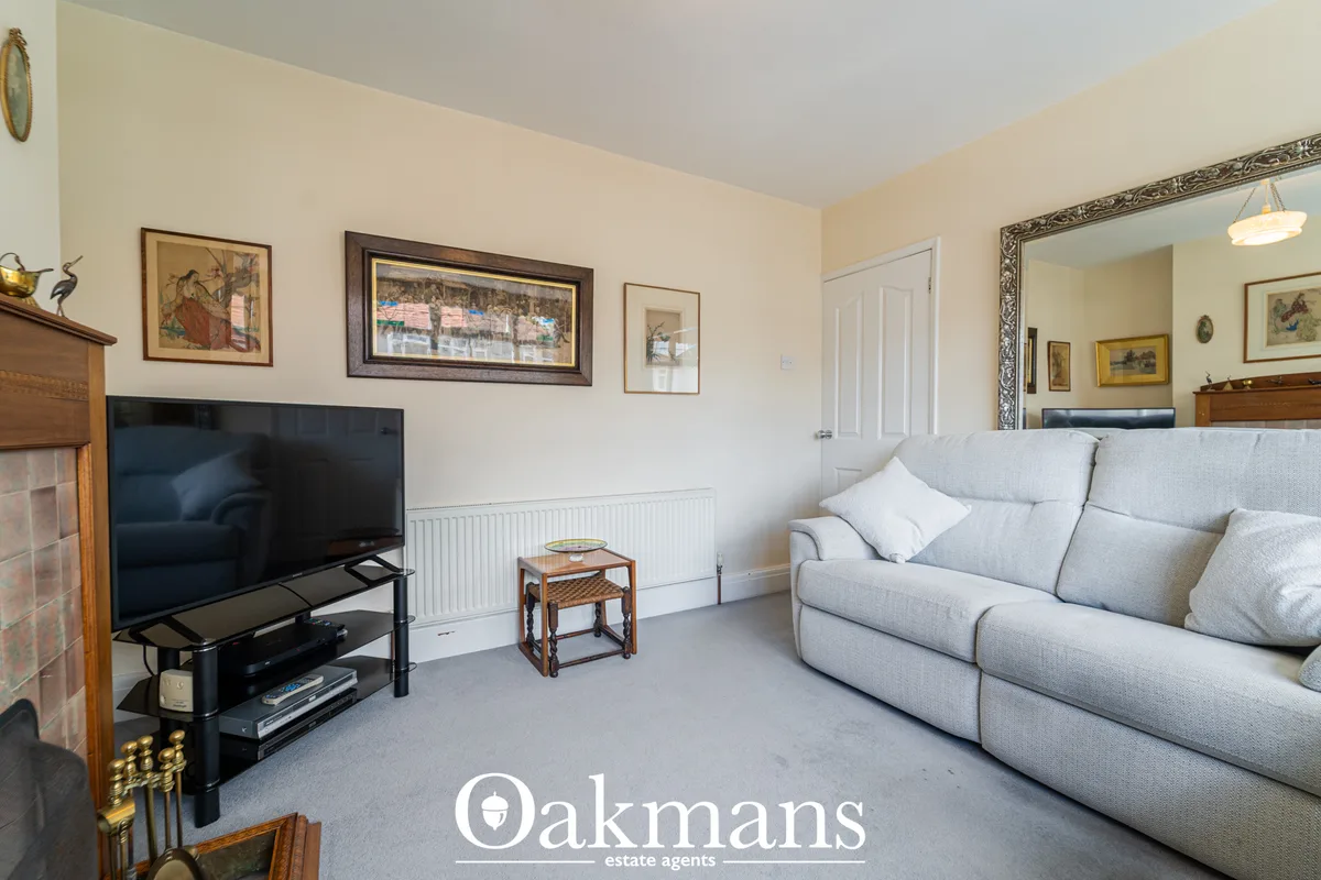 Spacious living room with light grey sofa, flat-screen TV on black stand, fireplace, framed artwork, ornate mirror and w