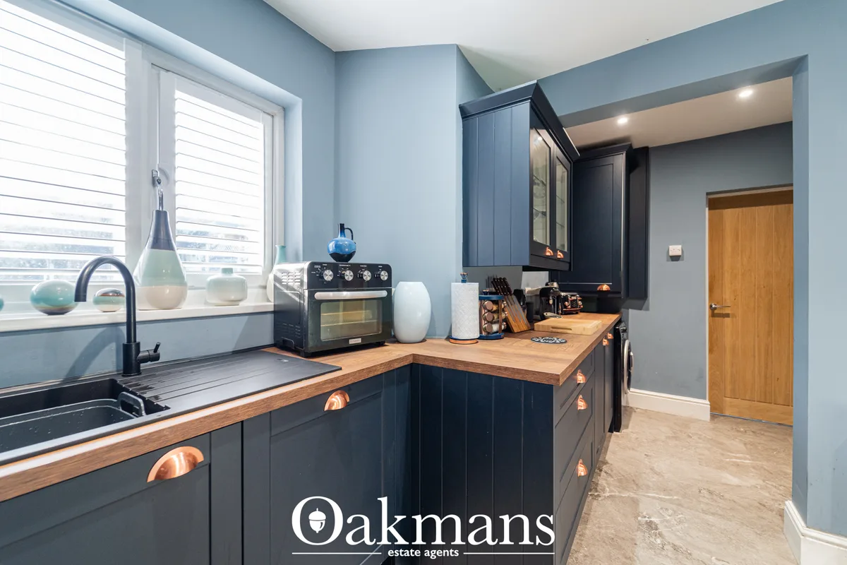 Modern kitchen with blue-grey cabinetry, wooden worktops, black range cooker, island unit, and blue walls with natural l