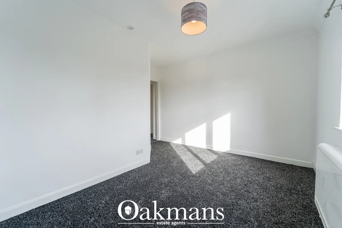 Bright entrance hallway with charcoal grey carpet, white walls, ceiling light fixture and natural sunlight from window