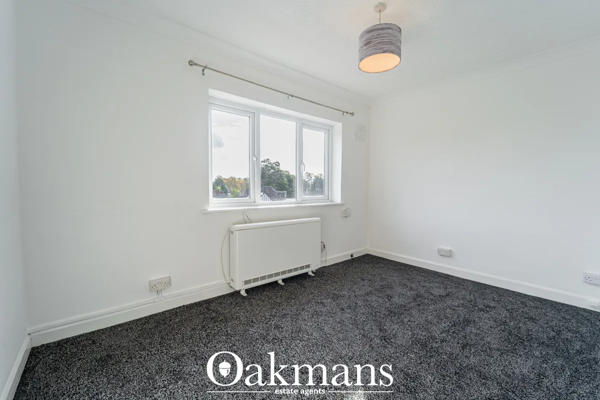 Bright bedroom with white walls, dark grey carpet, triple window with countryside views, white radiator and pendant ligh