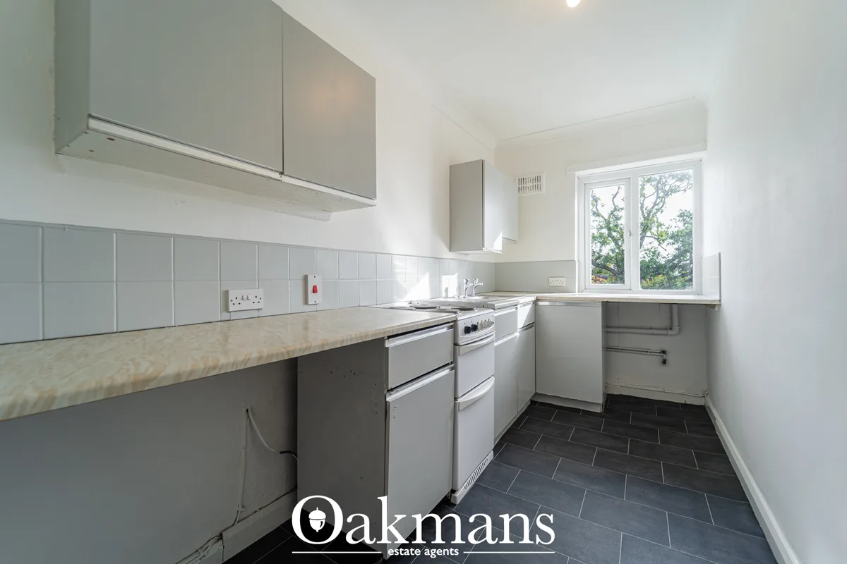 Modern fitted kitchen with grey cabinetry, white tile splashback, granite worktops, integrated appliances and window vie