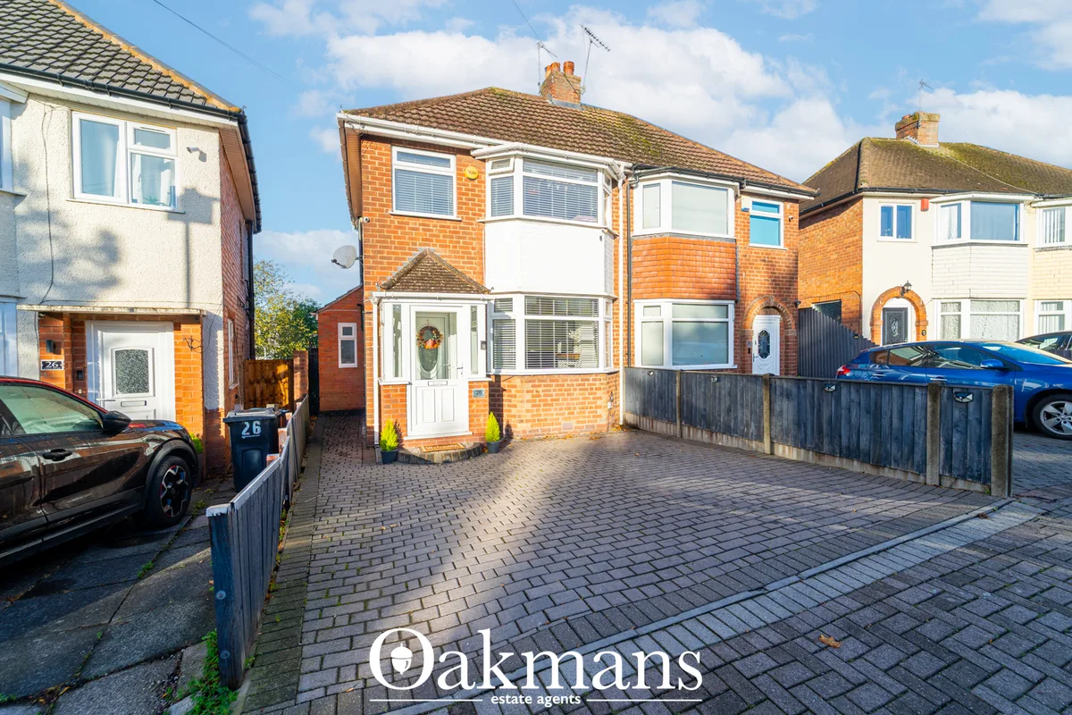 Semi-detached brick house with orange-red brickwork, white uPVC windows, tiled roof, paved driveway and front garden