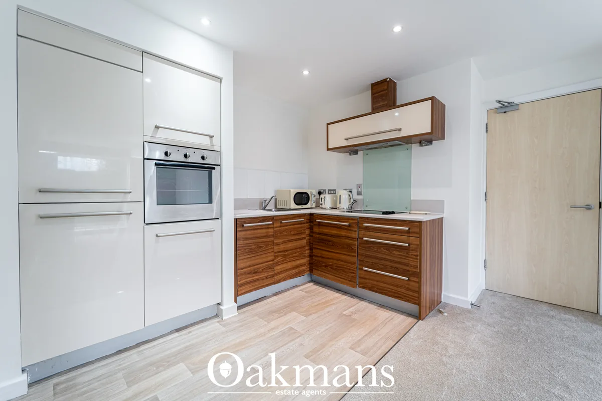 Modern kitchen with white gloss upper cabinets, walnut lower units, white countertops, built-in oven, mint green splashb