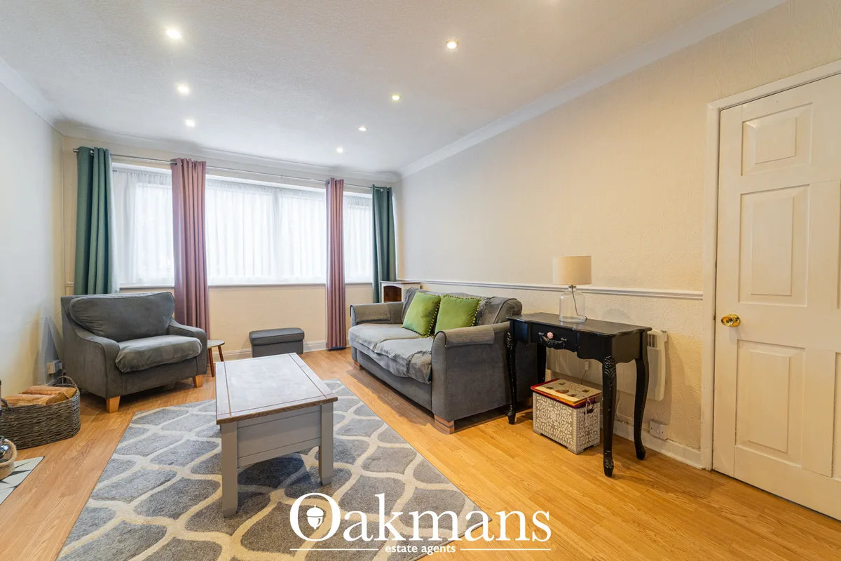 Spacious living room with grey sofa, armchair, wooden coffee table, recessed ceiling lights, large bay windows with mult