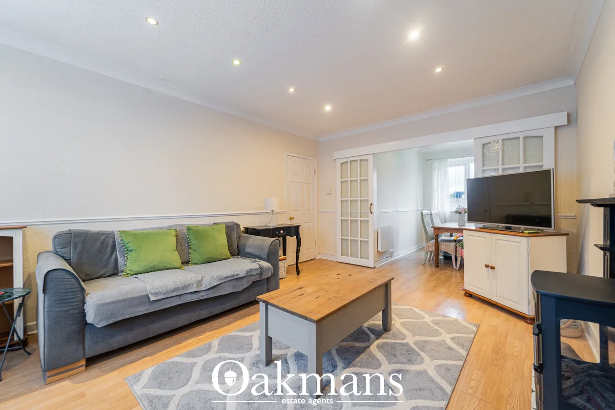 Spacious living room with grey sofa, wooden coffee table, TV cabinet, hardwood flooring, geometric rug, recessed ceiling