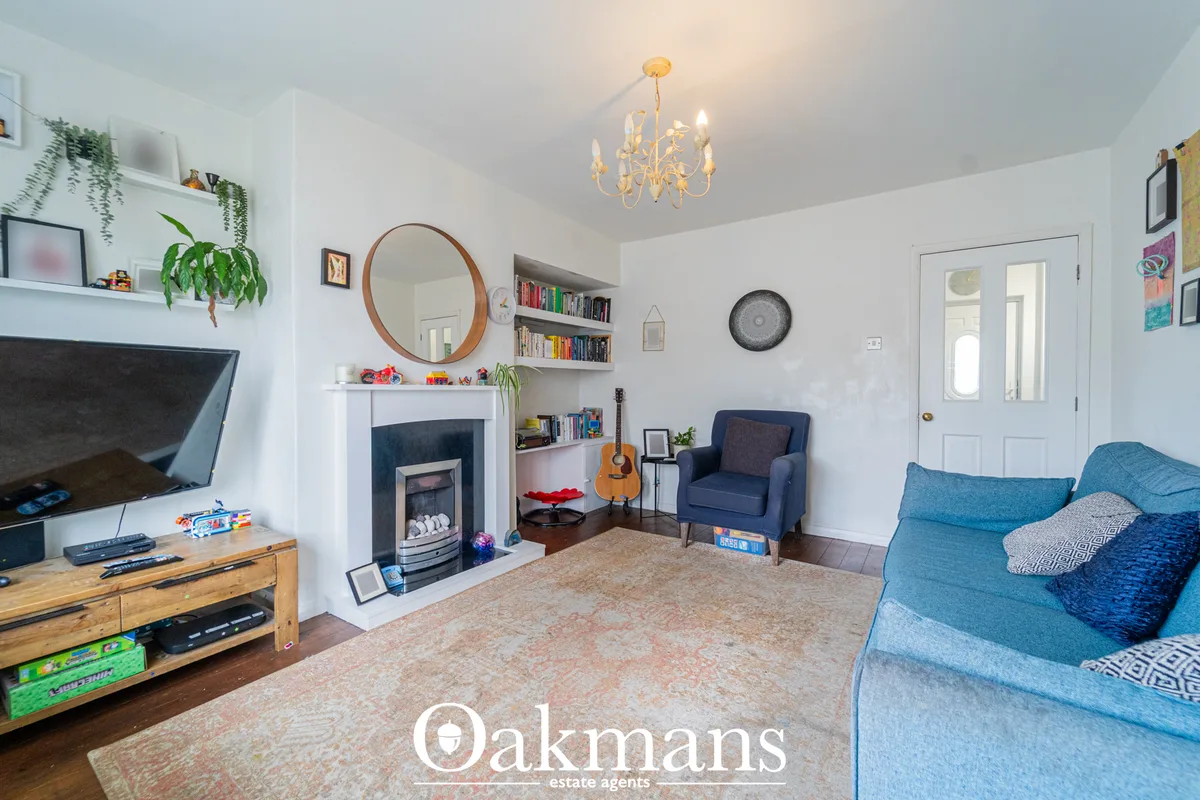 Bright living room with blue upholstered sofa, fireplace with built-in shelving, round wood mirror, wooden TV unit, and 