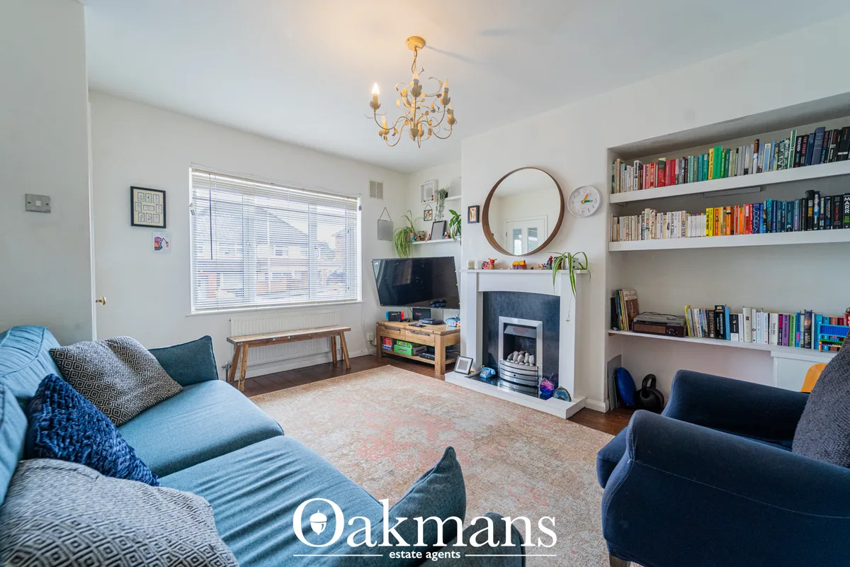 Bright living room with dual sofas, fireplace with mirror, built-in bookshelves, TV unit, pendant chandelier and large w