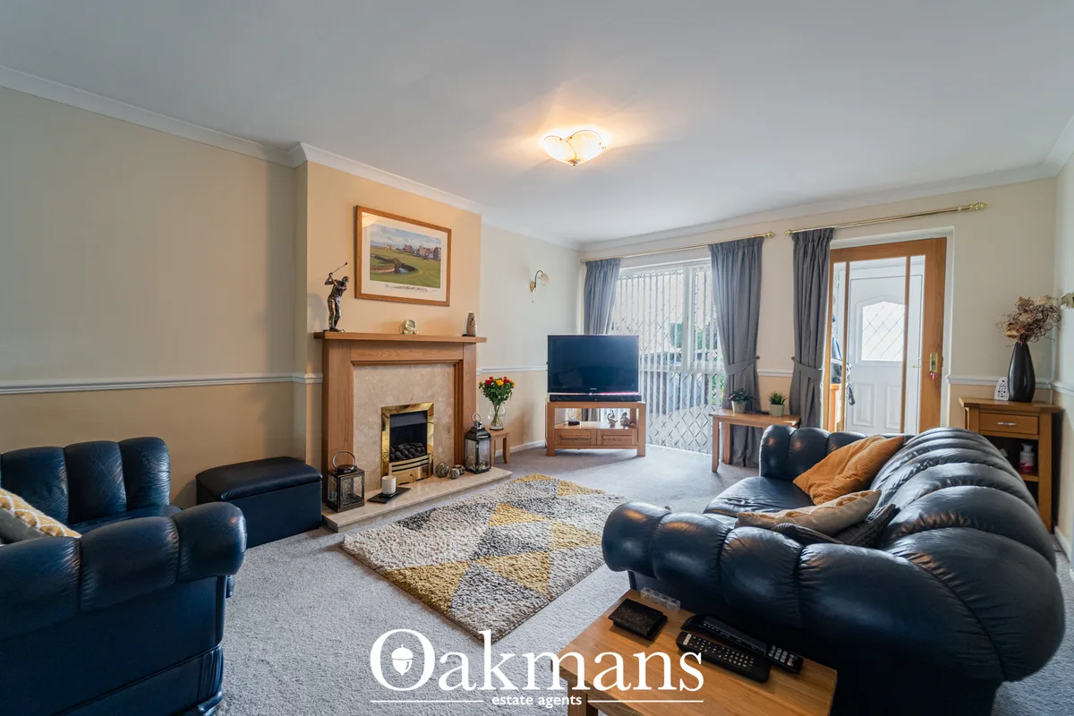 Spacious living room with blue leather sofas, fireplace with wooden mantel, TV on stand, patterned rug, patio doors with