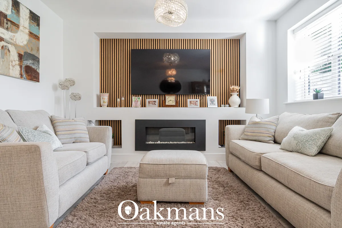 Contemporary living room with cream upholstered sofas, wall-mounted TV, fireplace with wooden slat feature wall, and neu