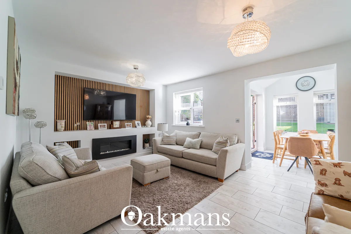Open-plan living room with beige corner sofa, electric fireplace, wooden-slat TV feature wall, pendant lighting and dini
