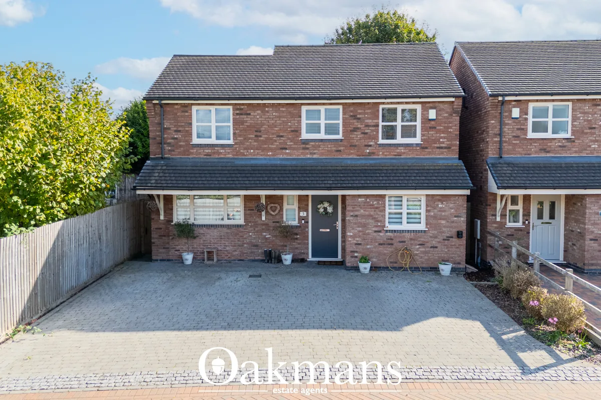 Front elevation of a brick semi-detached house with driveway, dark slate roof, uPVC windows and black entrance door