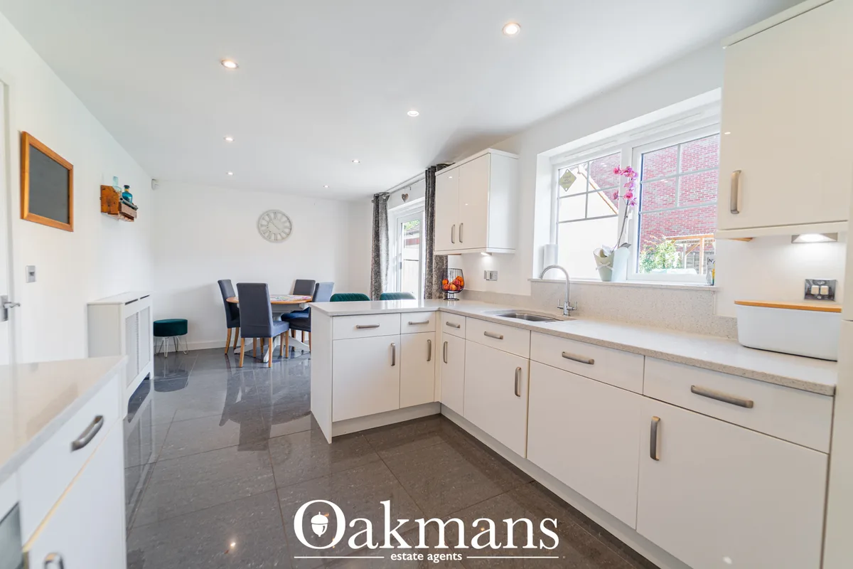 Modern open-plan kitchen with cream fitted units, granite worktops, stainless steel appliances, breakfast bar and dining