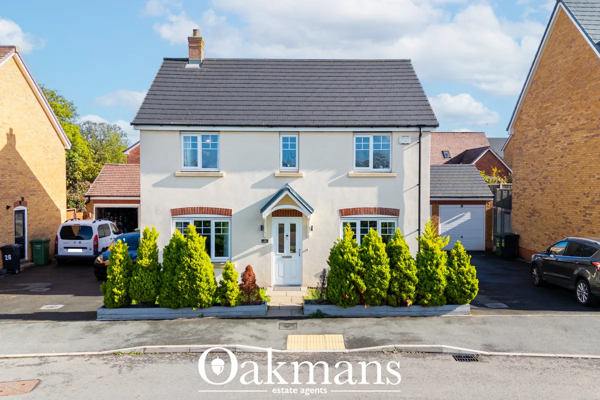 White rendered detached house with dark slate roof, three front windows, central white door, columned porch, manicured h