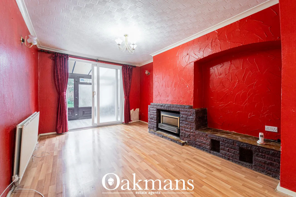 Spacious living room with bold red textured walls, wooden flooring, brick fireplace with electric fire insert, patio doo