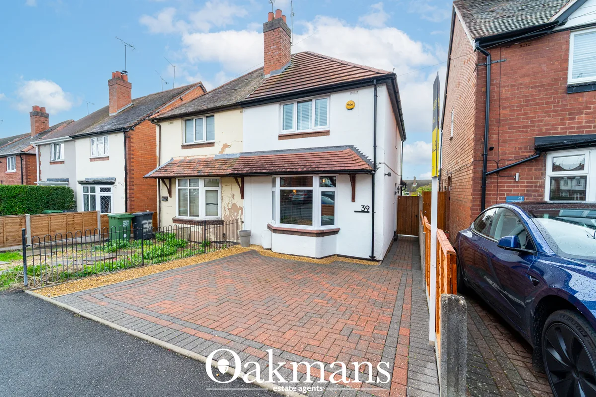 Semi-detached brick property with white rendered façade, tiled roof, driveway and front garden fencing