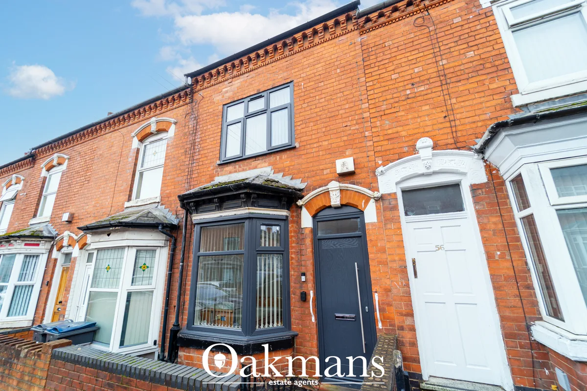 Red brick Victorian terraced house with ornamental cornice, white-framed windows, black entrance door with arch detail, 