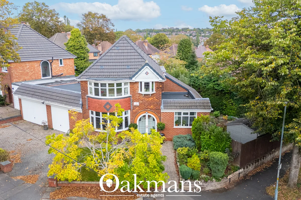 Aerial view of brick-built suburban home with pyramidal roof, circular bay window, arched entrance and manicured gardens