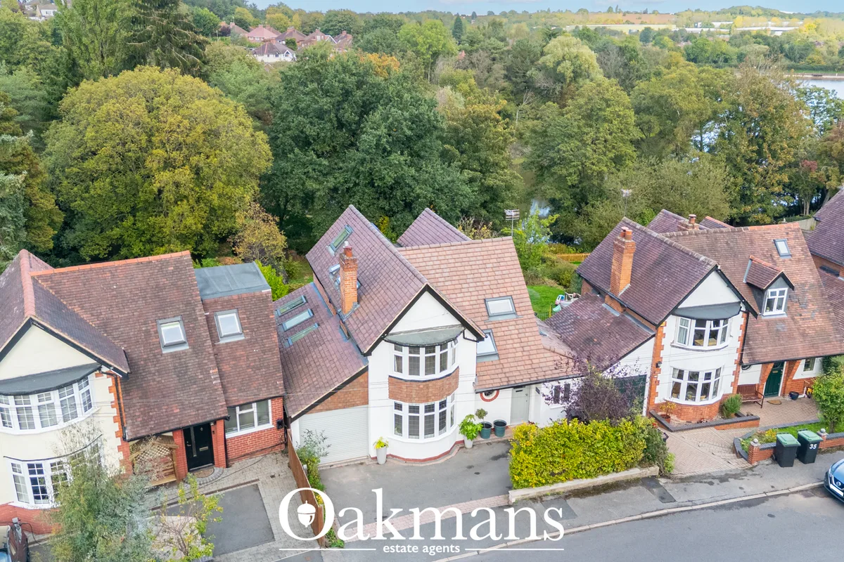 Aerial drone photograph of substantial brick-built residential properties with red-tiled roofs, mature trees, and rivers