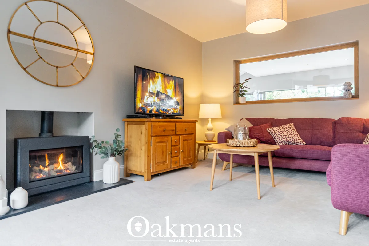Contemporary living room with burgundy sofa, wood furniture, fireplace with fire on-screen display, geometric mirror, wa