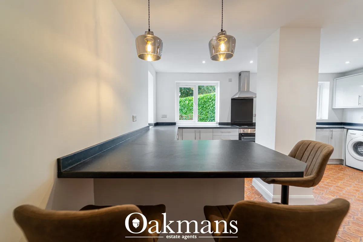 Modern open-plan kitchen with dark grey island, white units, black range cooker and pendant lighting overlooking garden