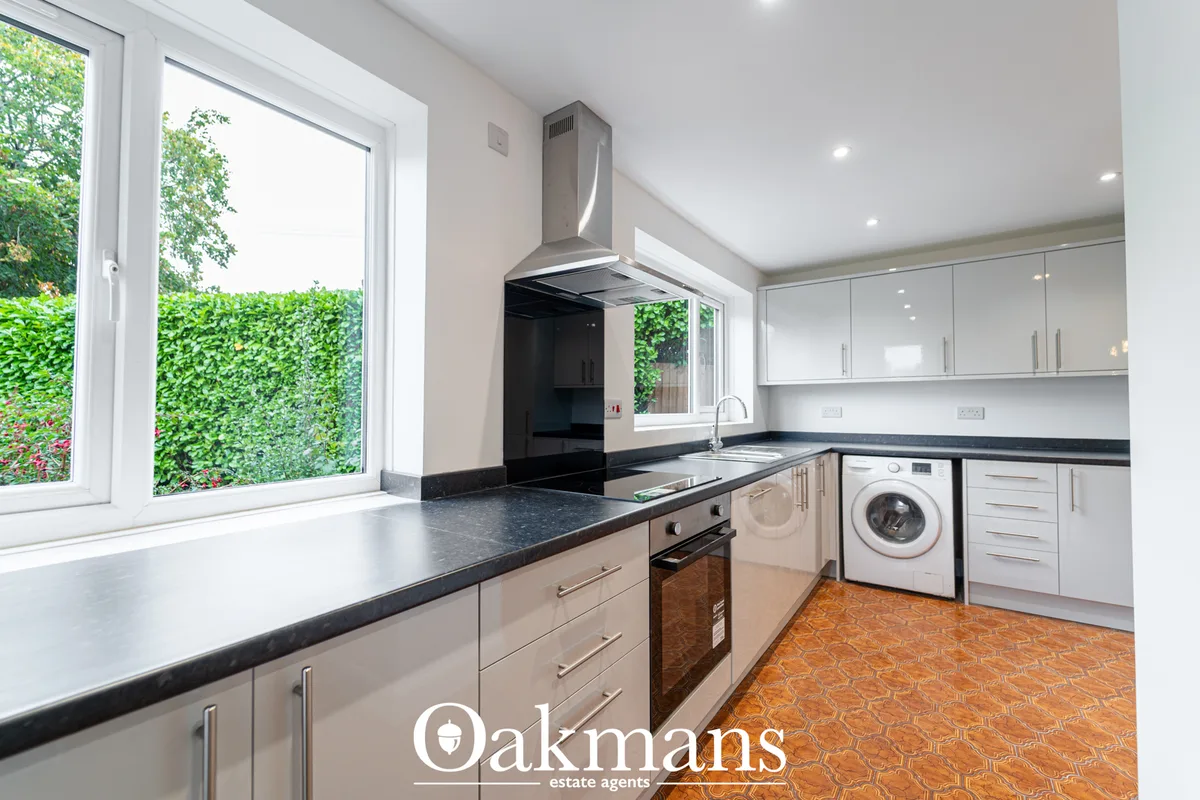 Modern fitted kitchen with white gloss units, dark granite worktops, stainless steel cooker hood, integrated appliances,