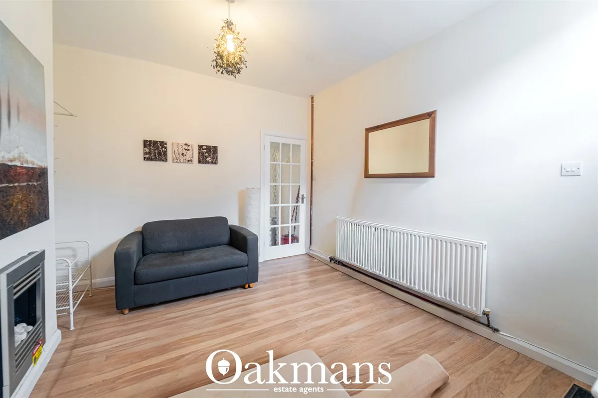 Spacious living room with dark blue sofa, wooden flooring, white radiator, fireplace, pendant lighting and wall mirror